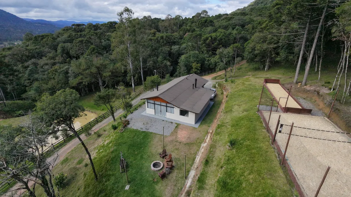 Área externa da cabana com espaço verde e serra ao fundo